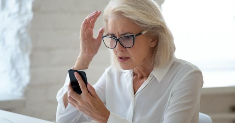 mulher olha celular indignada com o falso empréstimo